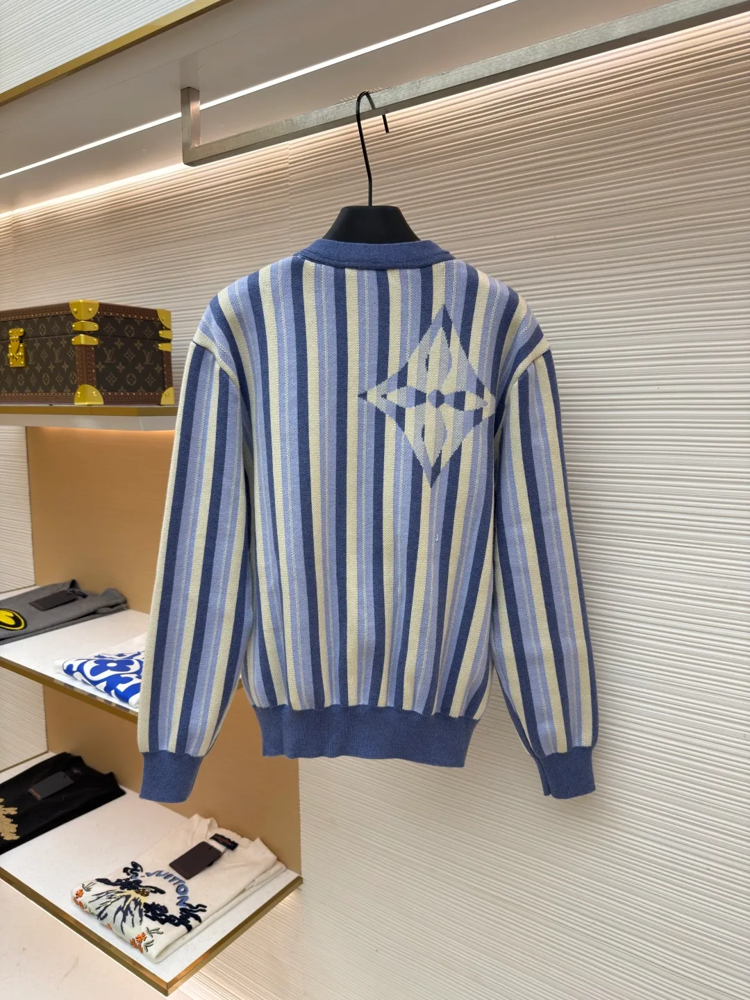 LOUIS VUITTON striped jacquard single-breasted sweater ●Original version: Purchased and developed for 15100 ●Item number: 1682314-C00 ●Fabric: wool fabric ●Technology: jacquard knitting ●Color: blue ●Version: fitted version ●Weight: about 930 grams ●Size: S-M-L-XL ●Description: This LV striped knitted cardigan is made of high-count worsted wool blended yarn. The double-ply threading process enhances the yarn's toughness. It is not easy to pill and has an outstanding drape feeling. The body of the garment adopts vertical jacquard weaving technology, with navy blue, light blue and off-white yarns interlaced with each other. The stripe width and spacing are precisely controlled by a computerized flat knitting machine, so that the color transition is natural and even. The LV letter jacquard on the left body has been debugged several times through plate making to ensure that the pattern is three-dimensional and clear. The V-neck, cuffs, and hem all use ribbing technology and are pre-shrunk to shape, making them less likely to loosen and deform after long-term wear. The buttons are made of custom-made metal, with matte sandblasting on the surface, and are hand-stitched with the seams of the body. The pockets use welting technology, and the edges are flat without jumpers. Every detail reflects the exquisite clothing craftsmanship and brand ingenuity. The overall wiring is straight and delicate, the fabric is comfortable and soft, and the color is consistent without color difference. It can be matched with the same style to create a fashionable look and control various occasions. Customized accessories, complete with three standards, same style for men and women!